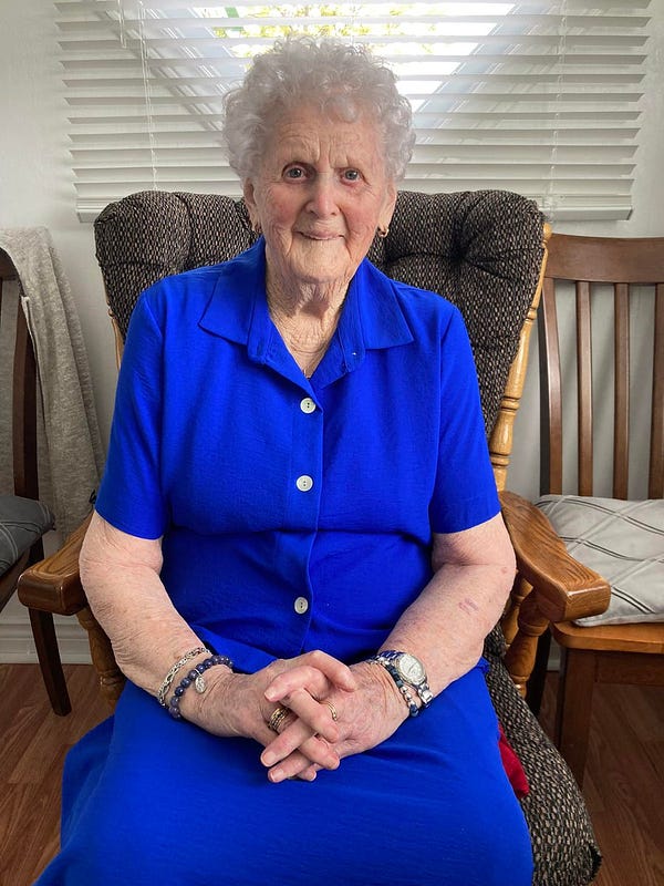 My dear grandmother sitting with hands folded in a rocking chair in the kitchen of her home in Calvert, Newfoundland.

She's wearing blue and the most beautiful smile you'll see on the occasion of her 101st birthday.