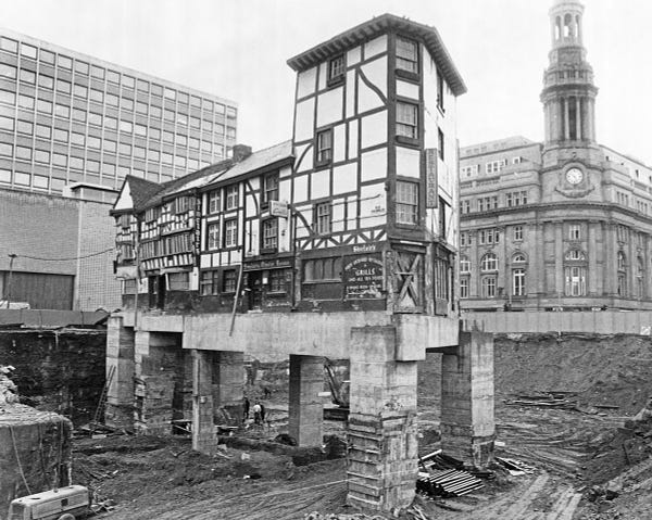 The Old Wellington Pub in Manchester, a half timbered building, left high and dry on brick and concrete pillars as the surrounding area is redeveloped