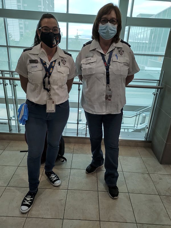 Two female airport security screening officers standing inside an airport.