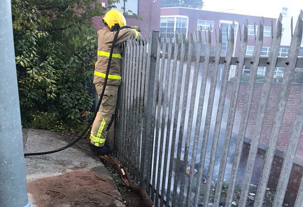 Firefighter reaching over railings to extinguish a fire
