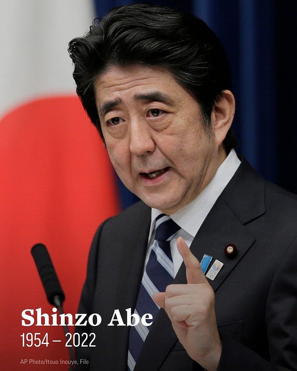Shinzo Abe speaks during a news conference in 2013. Text overlaid the image is his name and 1954 - 2022.