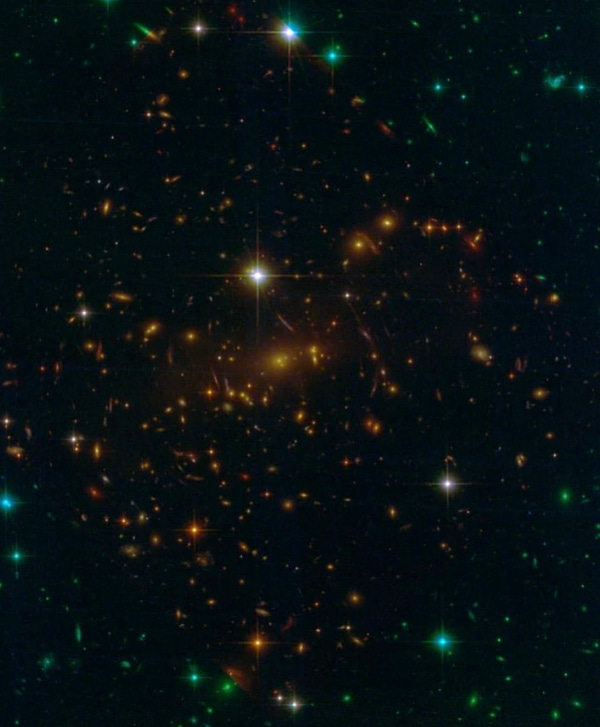 Hubble's view of SMACS 0732. Very dim-lit photo with more orange colors in the center and blue/green towards the outside of the photo. Few spots of bright white dots.