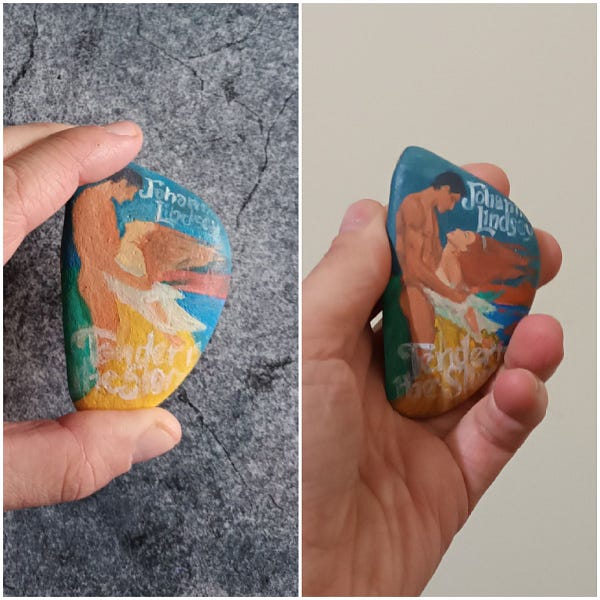 A collage of two photos showing the book cover Tender is the Storm by Johanna Lindsey in progress being painted on a rock. First photo shows a quick paint outline of the cover painted on. The second photo shows a bit more detail painted on the rock.