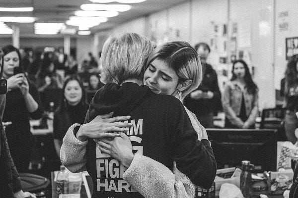 A black and white photograph of Elizabeth Warren hugging a smiling Anastasia Golovashkina.