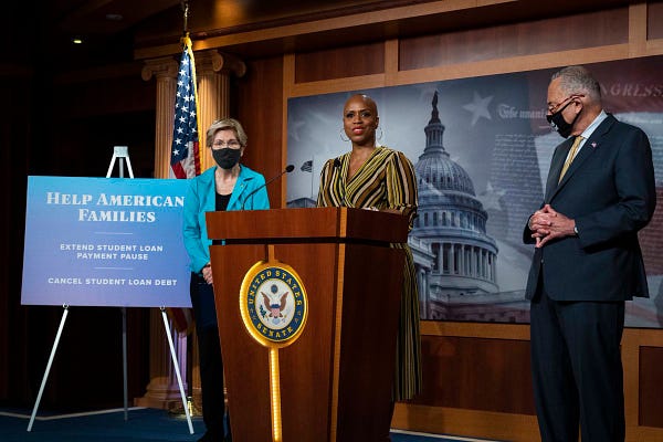 This is a photo of Ayanna at a podium speaking about student debt cancellation. Next to her are Senators Elizabeth Warren and Chuck Schumer.