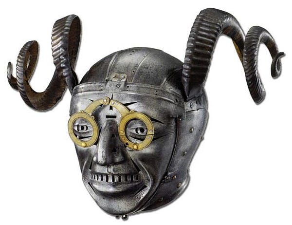 a photograph of a metal helmet with a toothy, bespectacled man's face molded out of the front and large, twisty metal horns