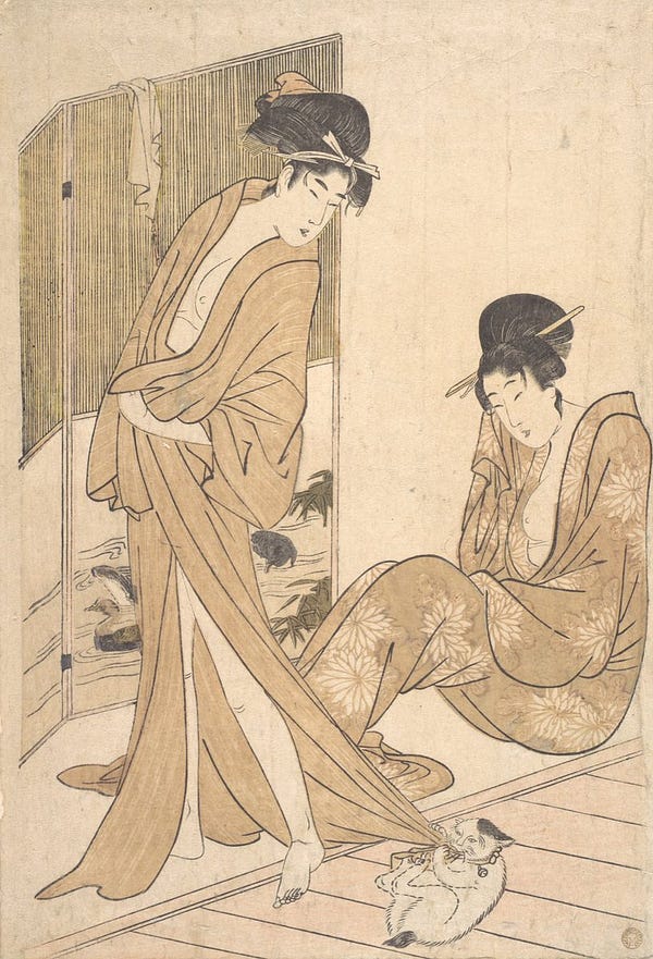 A Japanese woodblock print of two young women wearing loose bathrobes and their bath. One woman is standing and a small white and black bobtailed cat is on it's back playfully attacking the edge of her robe as she tries to pull it to safety.