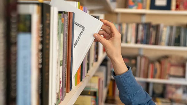 Stock photo of a person taking a book from a shelf 