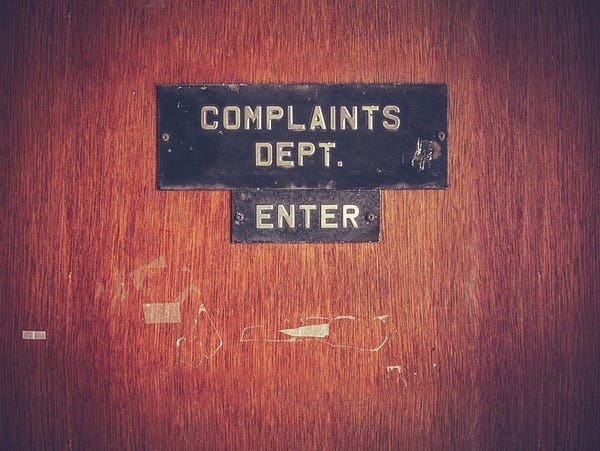 wood door with sign reading 'complaints department. enter'