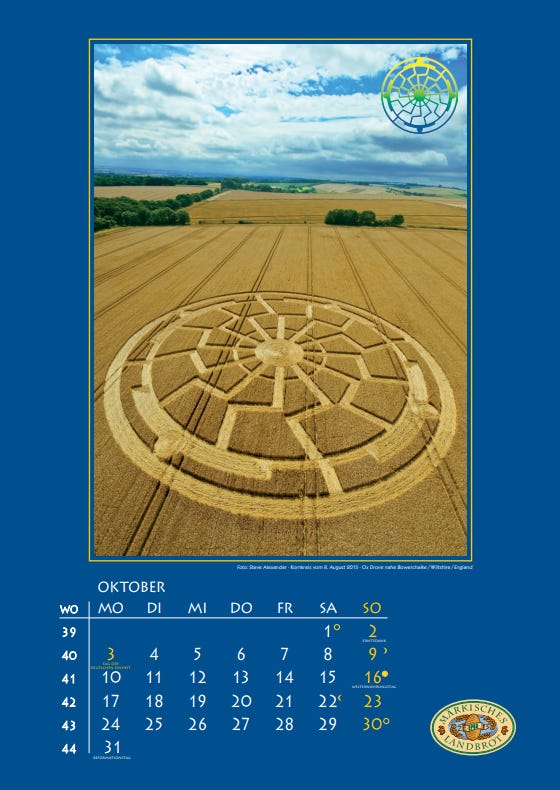 Blaues Kalenderblatt von "Märkisches Landbrot" für Oktober 2017 mit einem Farbfoto eines Kornkreises mit einer Schwarzen Sonne in einem Feld, darüer ein wolkenbedeckter Himmel. 