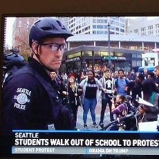 Officer Eric Walter in a Bike helmet on a news broadcast covering an anti-Trump protest from 2017