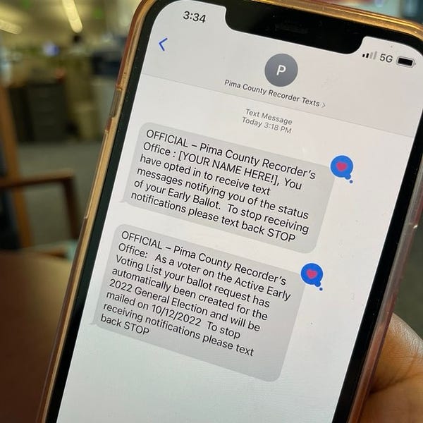 A cellphone is displayed with messages announcing that the voter has signed up for text alerts about the status of their ballot.