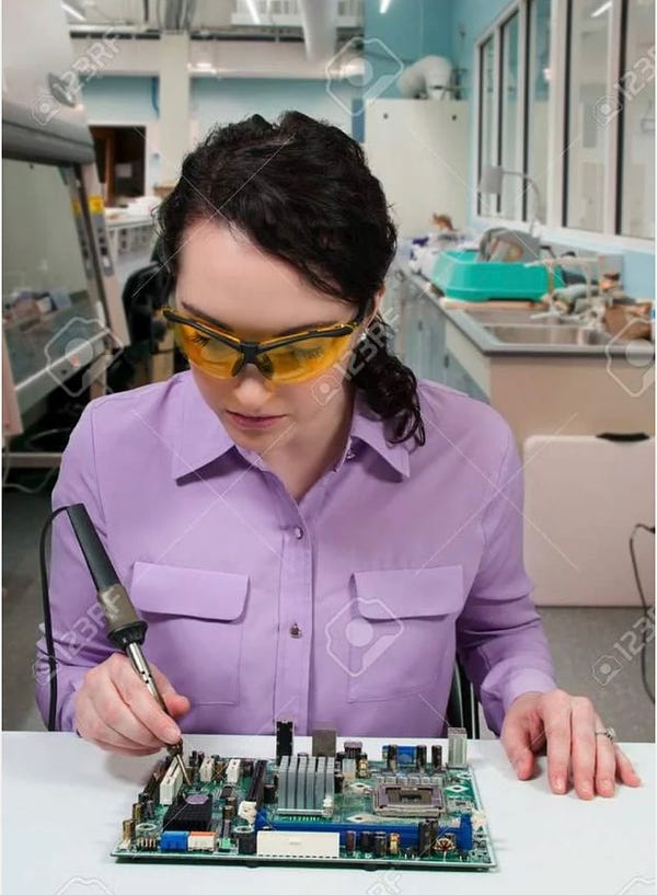 A woman OF SCIENCE in a biology lab, not a wearing a labcoat but some kind of rifle range glasses, soldering a motherboard by grasping the soldering iron where it gets hot, in a desperate attempt to let the pain transport her back to 2014, when life was good, life was happy.