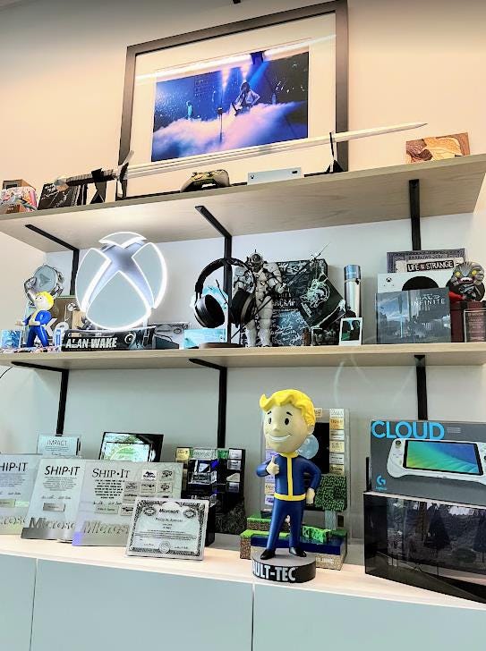 A Vault Boy statue prominently displayed on a shelving unit full of gaming memorabilia