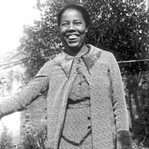 Foto em preto e branco de Antonieta de Barros sorrindo, ela veste um casaco de lã por cima de um vestido do mesmo material.