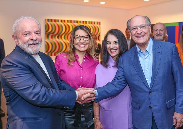 Lula e Geraldo Alckmin sorriem de mãos dadas, ao lado de Janja e Lu Alckmin