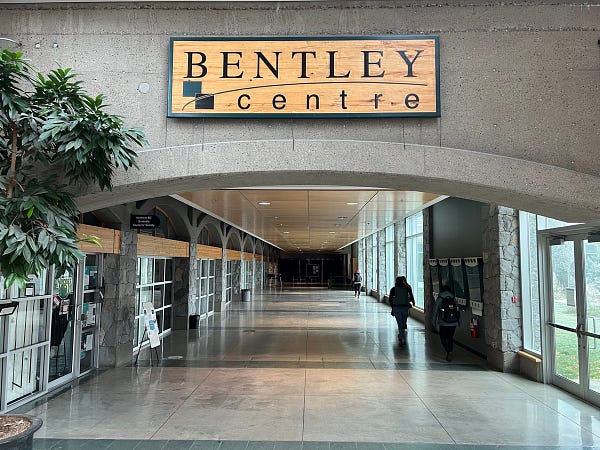 Sign for the Bentley Centre prominent in the photo as people walk down the hallway.  