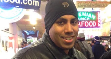 German Barreto, aged 30 something, in a black leather jacket and a beanie in the walkway of Pike Place Market
