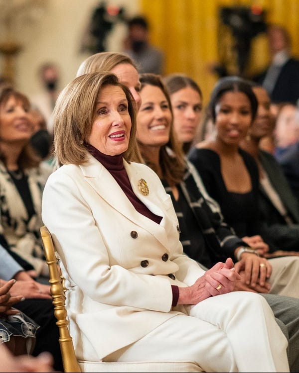 Speaker Pelosi sits and wears a white suit