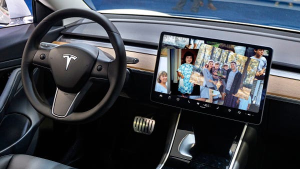 A tesla dashboard screen with a photo collage of someone's family.