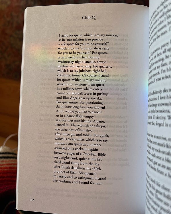 Page 12 in an open book of poetry; a rainbow from a prism shines across the poem “Club Q” by James Davis on the page:

CLUB Q

I stand for quest, which is to say mission,
as in "our mission is to provide
a safe space for you to be yourself,"
which is to say "it is not always safe
for you to be yourself." For queen,
as in a six-four Cher, hosting
Wednesday-night karaoke, always
the first and last to sing. For quarters,
which is to say jukebox, eight ball,
cigarettes, home. Of course, I stand
for queer. Which is to say unique,
which is to say alone. I am queer
in a military town where cadets
count out football scores in pushups
and Blue Angels bar up the sky.
For quarantine. For questioning.
As in, how long have you known?
As in, would like to dance?
As in a dance floor, empty
save for two men kissing. A patio,
fenced in. The warmth of a firepit,
the sweetness of his saliva
after three gin and tonics. For quick,
which is to say alive, which is to say
mortal. (poem continues)