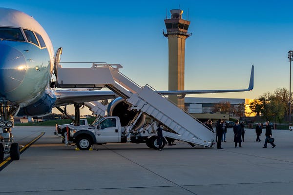 Secretary Blinken walks towards the stairs of a plane.