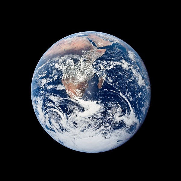 An image of the Earth, a perfectly round ball, set against the blackness of outer space. Through swirling clouds, the continent of Africa and the island of Madagascar can be seen; Antarctica is just visible at the very bottom of the Earth, and the Arabian peninsula at the top. The Atlantic and Indian Oceans are a deep, rich blue, giving this photo its common name: the Blue Marble.