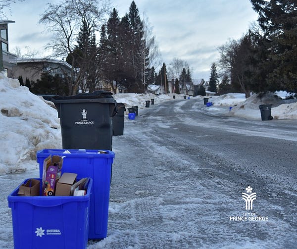 City garbage cans and recycling containers wait on the curb for collection during the winter