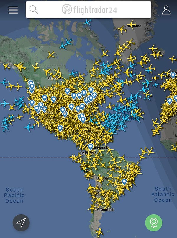 Flight radar 24 map of North and South America. Yellow planes are covering the entirety of North America, except for northern Canada. Lines of Blue & yellow planes are crossing the Atlantic Ocean.