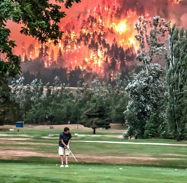 Ein Mann spielt Golf während im Hintergrund ein Waldbrand herrscht.