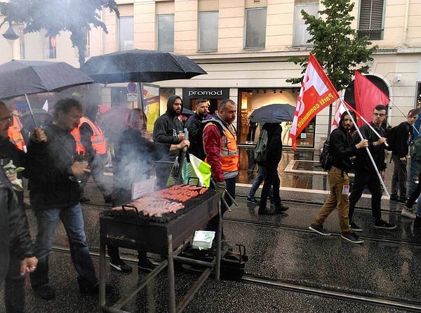 strikers of the french railway union walking down the street with a mobile barbecue that's connected to tram rails