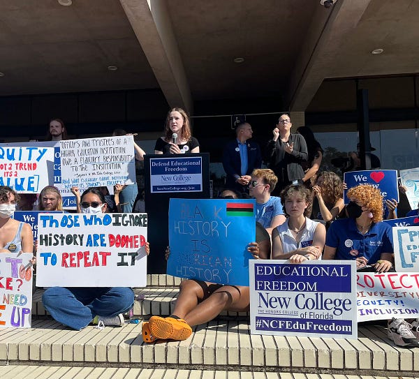 Photo of students with signs at New College of Florida around a student speaker