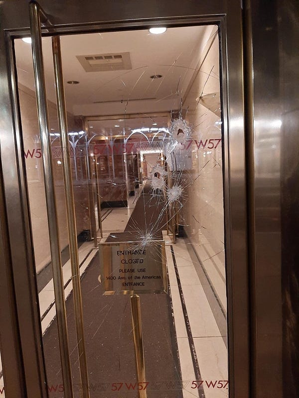 Front door of 57W57, a glass door, which shows multiple impact points and the glass shattered.