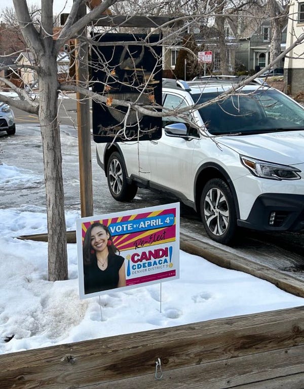 A Candi CdeBaca yard sign in the snow in front of a house