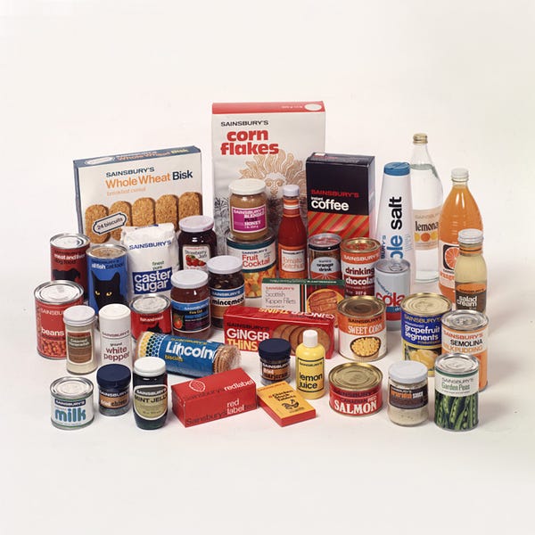 A photo of food items from the 70s with retro packaging. There is a wide variety of items, from corn flakes and sea salt, to ginger thins and lemon juice.