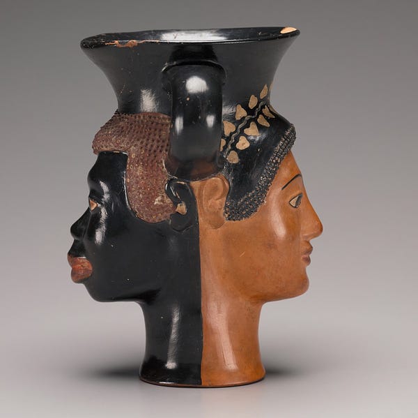 Two handled Greek wine cup with two faces, one on each side: one of a Black African man and one of a Greek woman