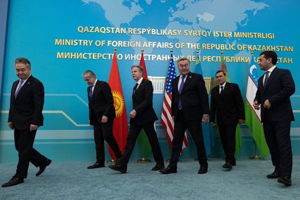 Secretary Blinken and members of the C5 walk away after an official photo. The flags of all participating countries are behind the officials.  
