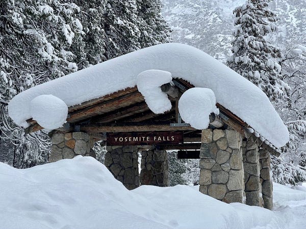 Yosemite Falls shuttle stop shelter with piles of snow surrounding it and significant snow on the roof.