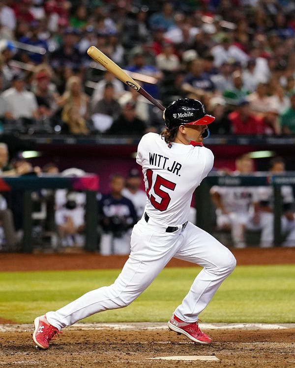 Bobby Witt Jr. finishing his swing after hitting an RBI double in a white Team USA uniform at the World Baseball Classic against Team Mexico at Chase Field.