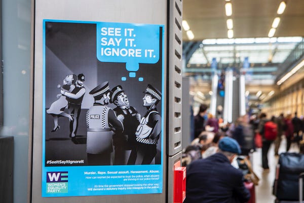 A poster of a black and white illustration of police officers ignoring a woman being attacked by a fellow police officer. The words, "See it, say it, ignore it" are on the top right of the poster, and the poster is in a busy train station. 