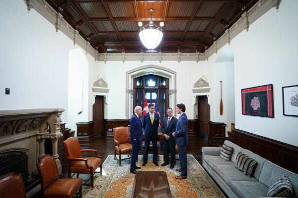 Prime Minister Justin Trudeau, President Joe Biden, Michael Kovrig, and Michael Spavor are standing in the Prime Minister’s office. Canadian and American flags are visible behind them.