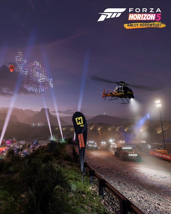 A rally race comes over a hill with a  helicopter above at night
