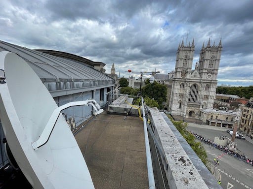 1st photo: Standing on the roof of Methodist Central Hall, in the foreground a satellite dish, and Westminster Abbey in the background. 2nd: Balcony full of people and studio equipment overlooking Westminster Abbey