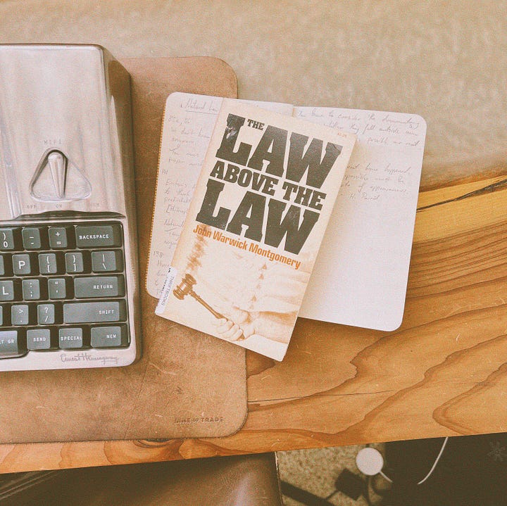 The book being reviewed is pictured on a desk with a writing instrument and notebook.