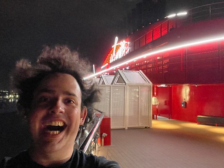 1st photo, me sat at an audio mixing desk in the ship's technology office. 2nd: Selfie on the deck in front of the Virgin logo on the chimney. 3rd: On my knees installing cabling in an access panel. 4th: Standing out on the open shell door at the starboard bow. I'm wearing life jacket and harnesses.