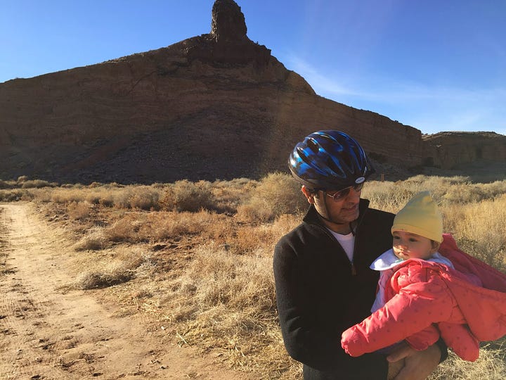 Baby and mom sitting near campfire; baby and dad in front of New Mexico hill