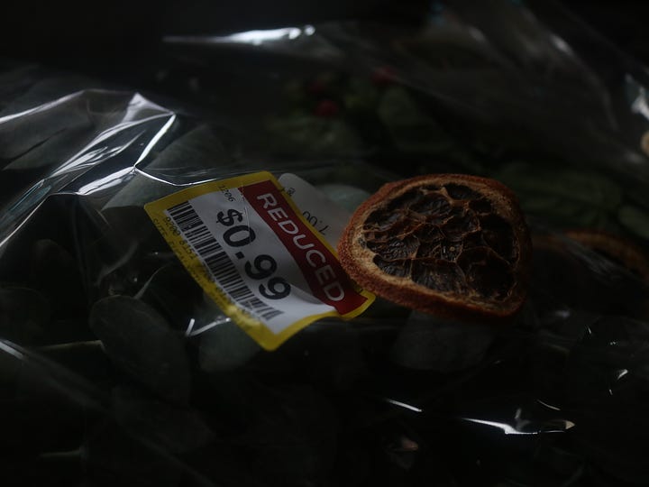 Price tag on grocery store flowers in plastic sleeve. Next arranged flowers in a vase on tray with candle and decor.