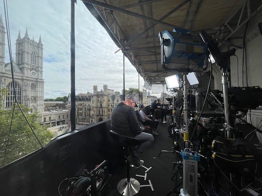 1st photo: Standing on the roof of Methodist Central Hall, in the foreground a satellite dish, and Westminster Abbey in the background. 2nd: Balcony full of people and studio equipment overlooking Westminster Abbey