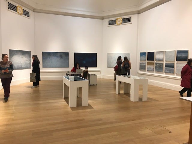 a group of people gathered in an art gallery, all smiling