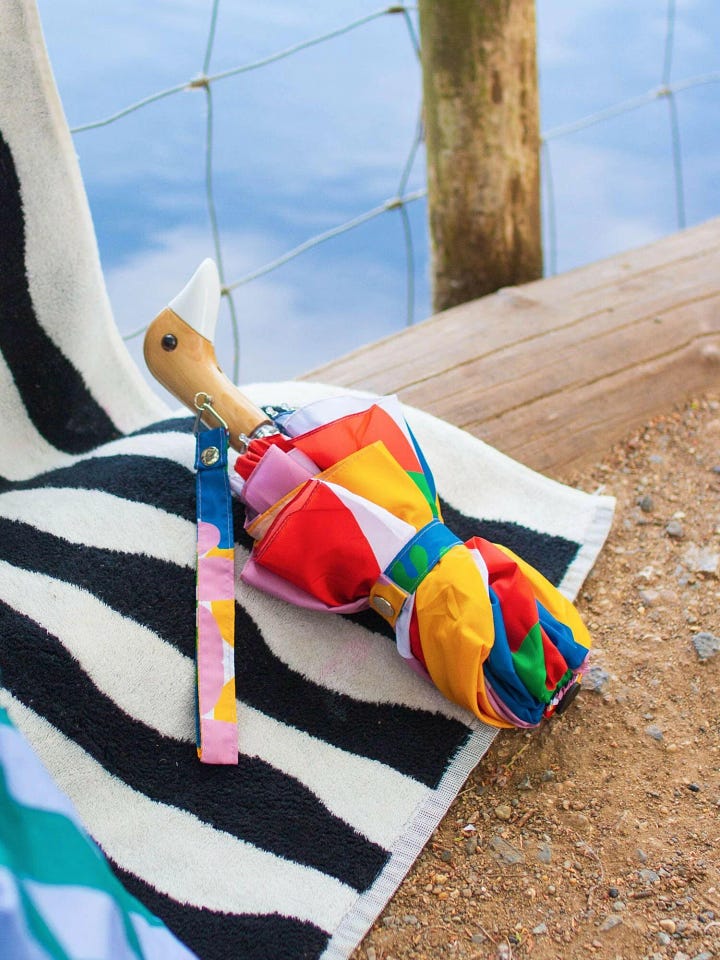 Umbrella featuring Matisse-inspired abstract shapes in bold colors, paired with a birch wood duck-head handle. A stylish, artistic choice for rainy days.